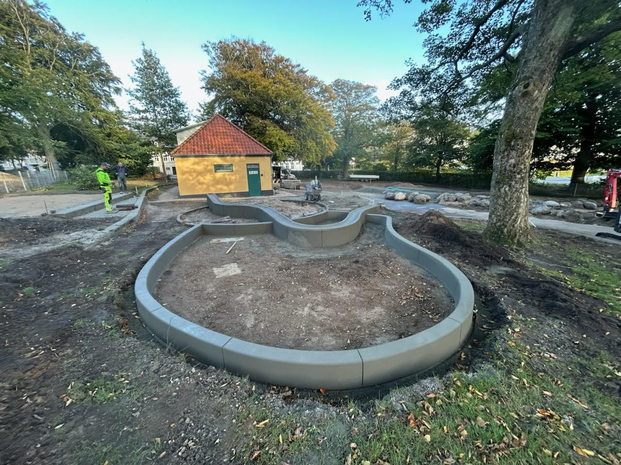 Concrete water gulley running through the middle of a park, slipformed on site by a ScandiCurb crew