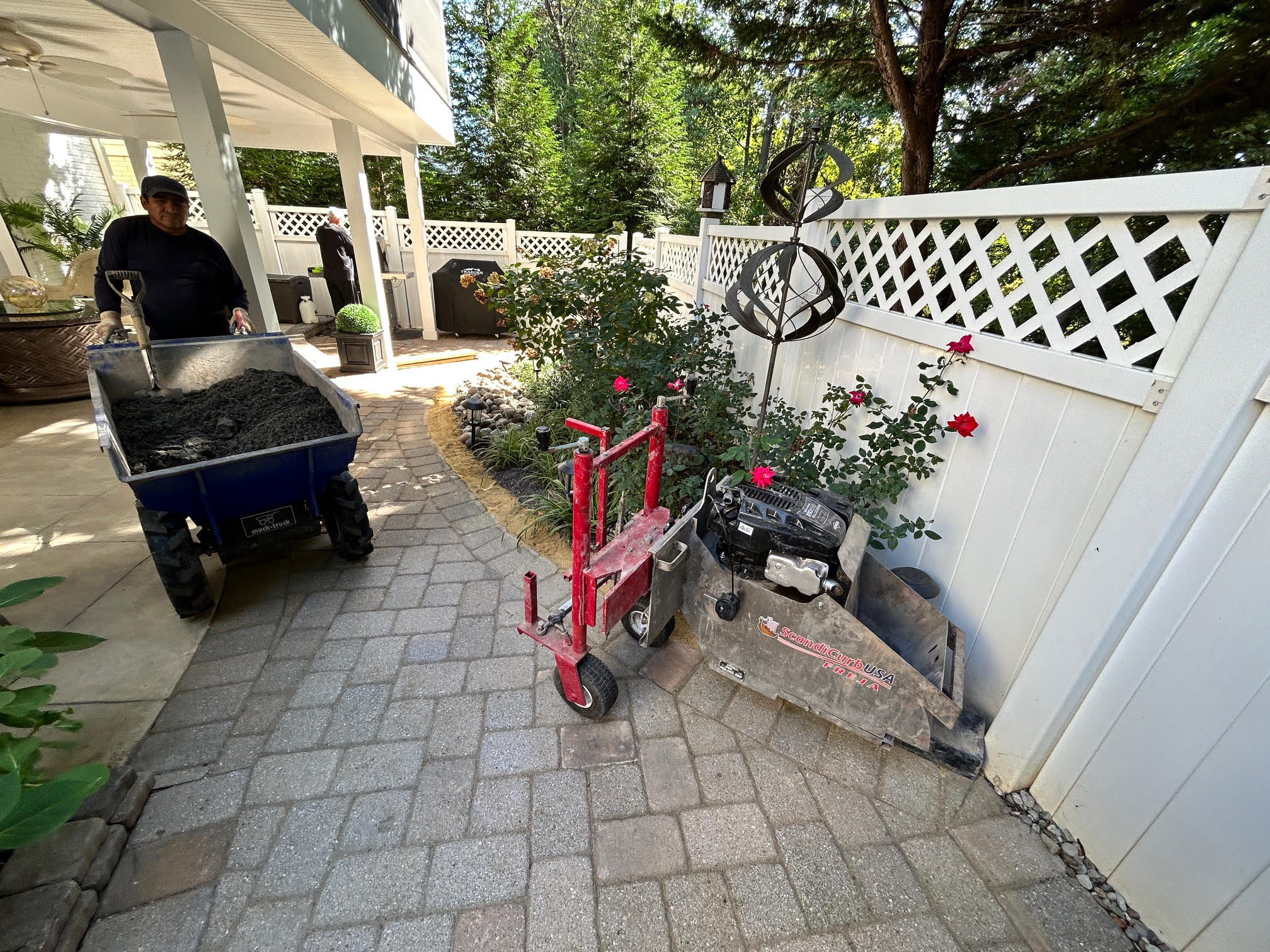 FREJA slipform machine pouring residential curb along a paver patio