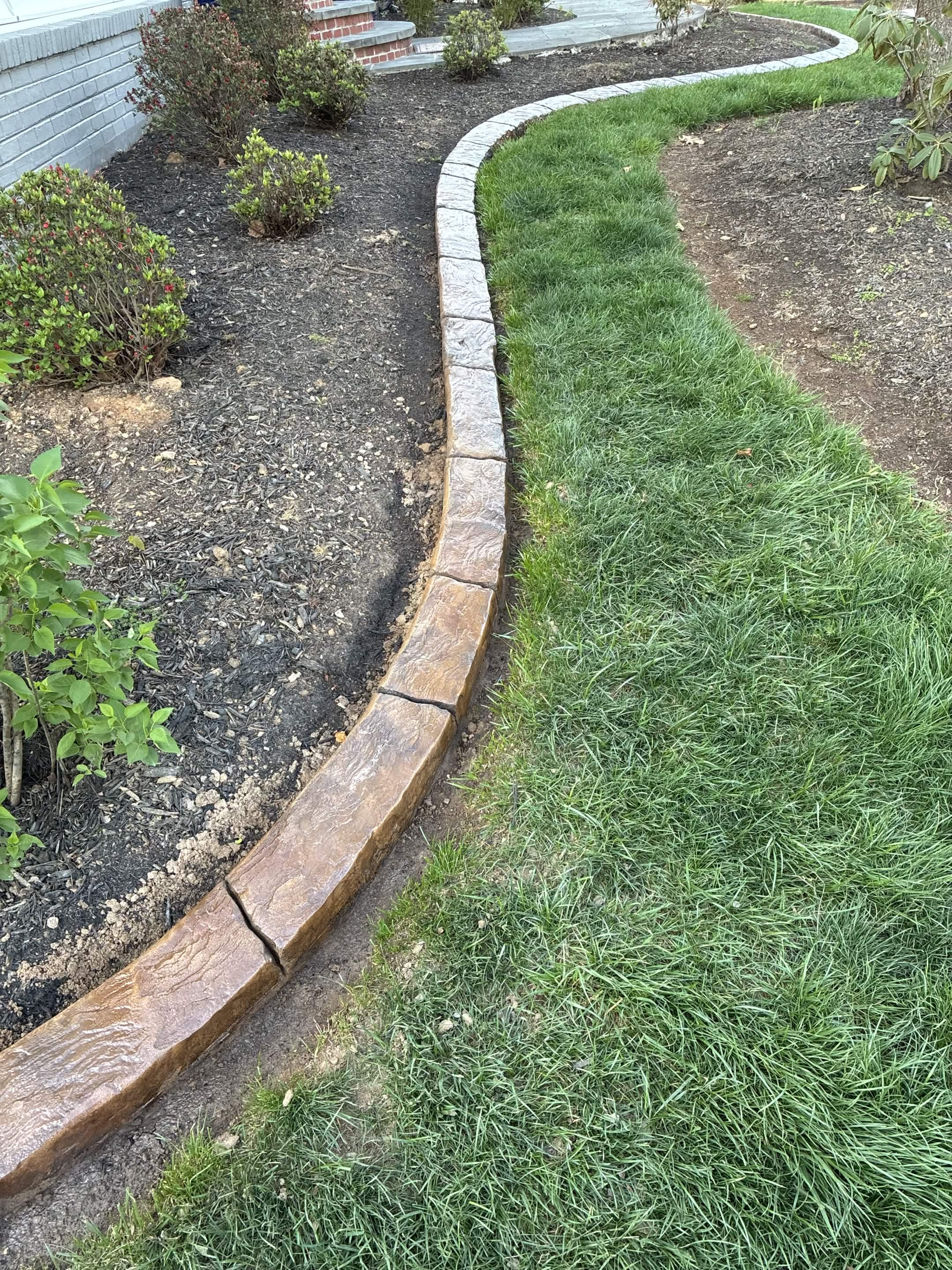 Standard residential concrete curb poured with a LOKE slipform machine along a planting bed